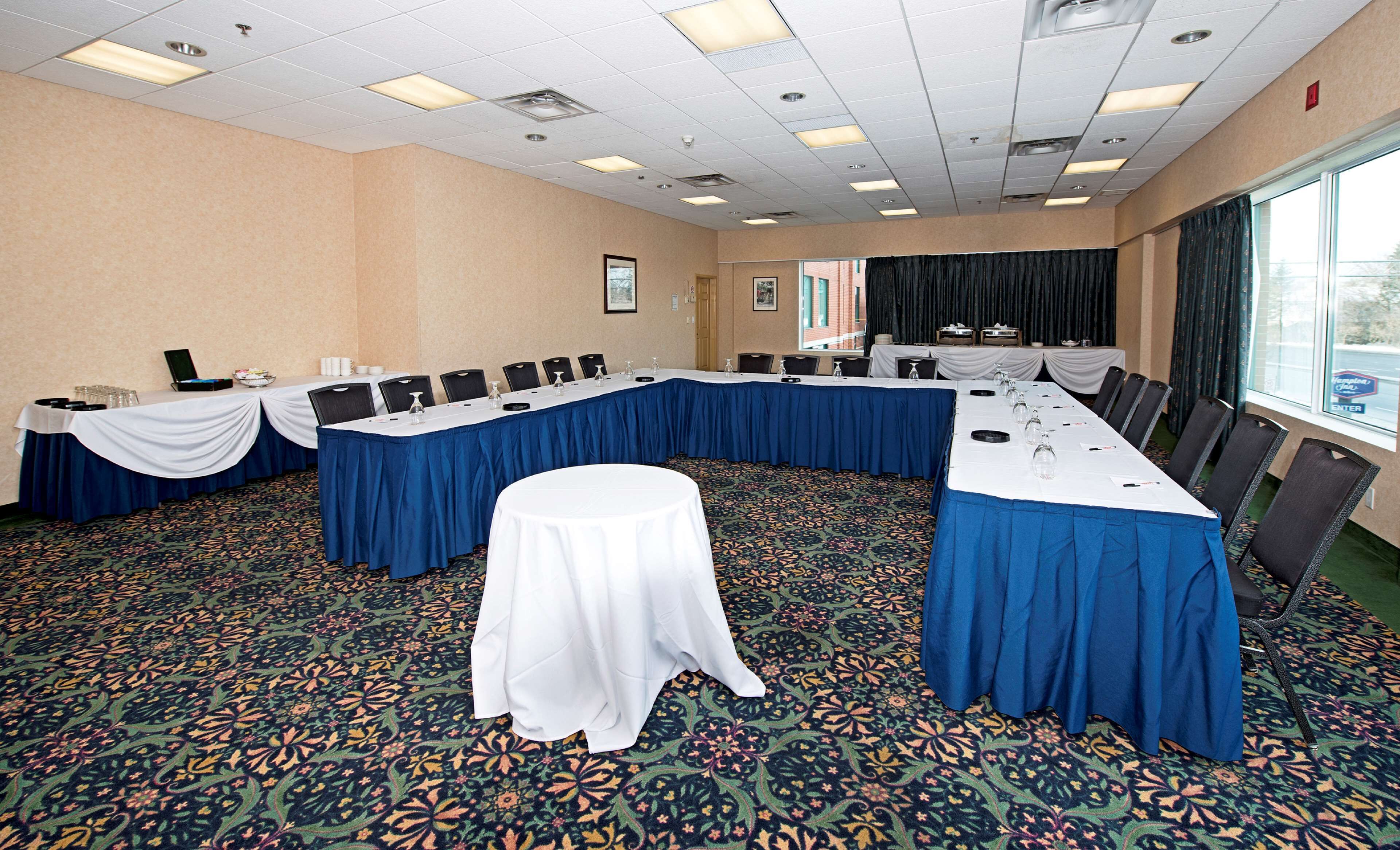 A conference room with a long table, chairs, and a smaller table in the center.