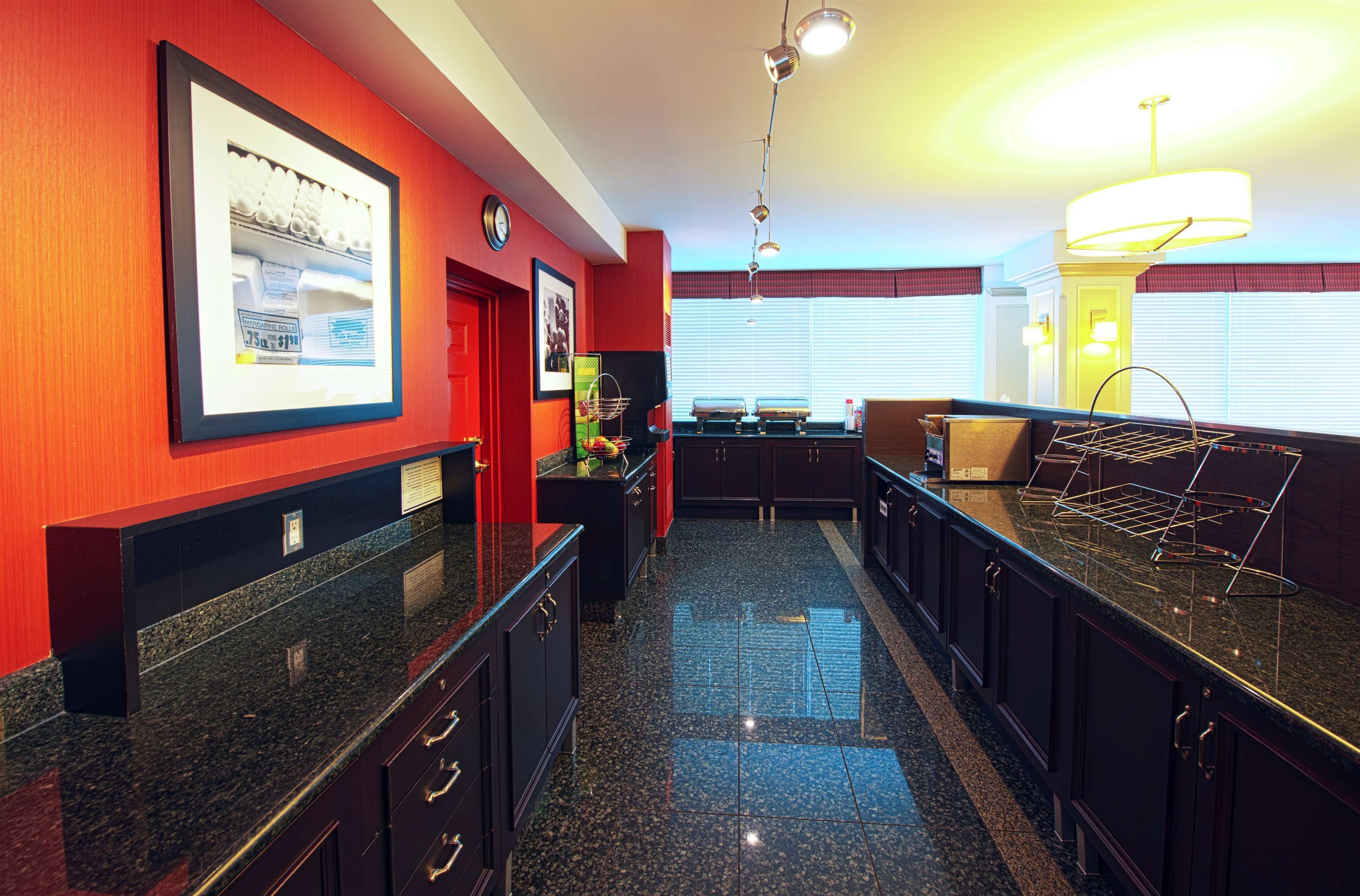 A kitchen with granite countertops, dark cabinetry, and a red accent wall.