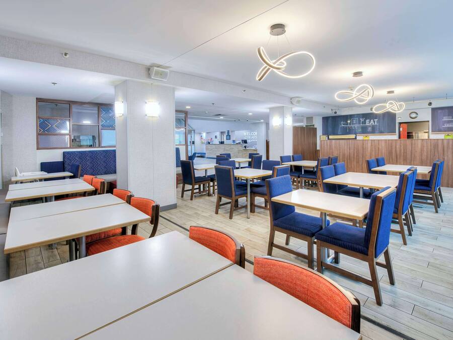 A modern restaurant with multiple tables and booths, a counter area, and a visible menu board.