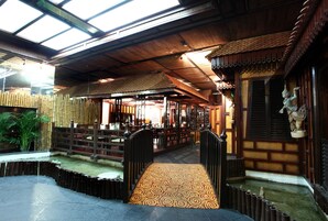 Un interno in legno tradizionale con un percorso centrale, decorazioni in bambù e una statua.