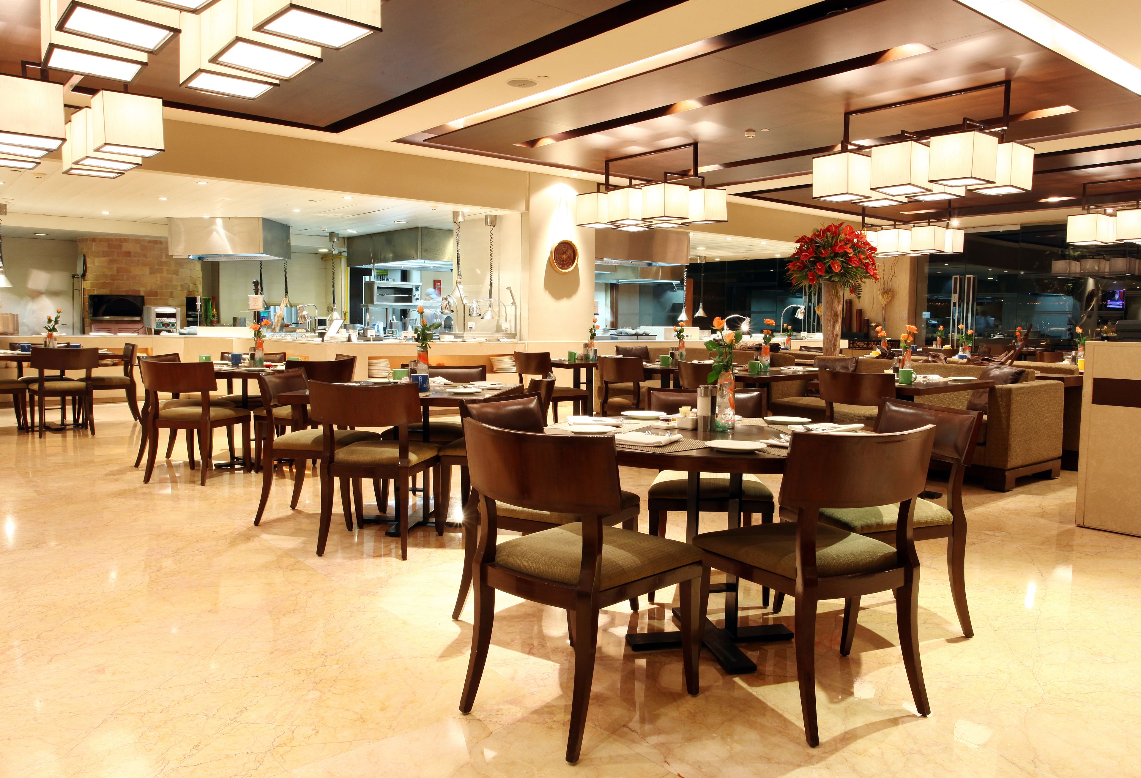 Un comedor moderno con suelo de mármol, sillas de madera e iluminación contemporánea.