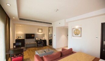A modern hotel room with a bed, a desk, a chair, a TV, and a sofa.