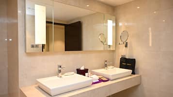 Een moderne badkamer met twee wasbakken, een grote spiegel en een tas voor een haardroger op het aanrecht.