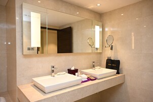 A modern bathroom with two sinks, a large mirror, and a hair dryer bag on the counter.