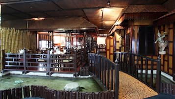 Un interior japonés tradicional con suelo de tatami, muebles de madera y una fuente decorativa.
