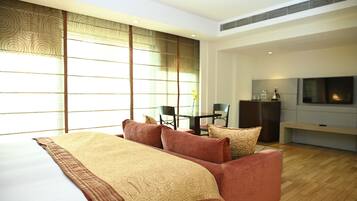 Una habitación de hotel moderna con una cama grande, un sofá, un televisor y un área de comedor.
