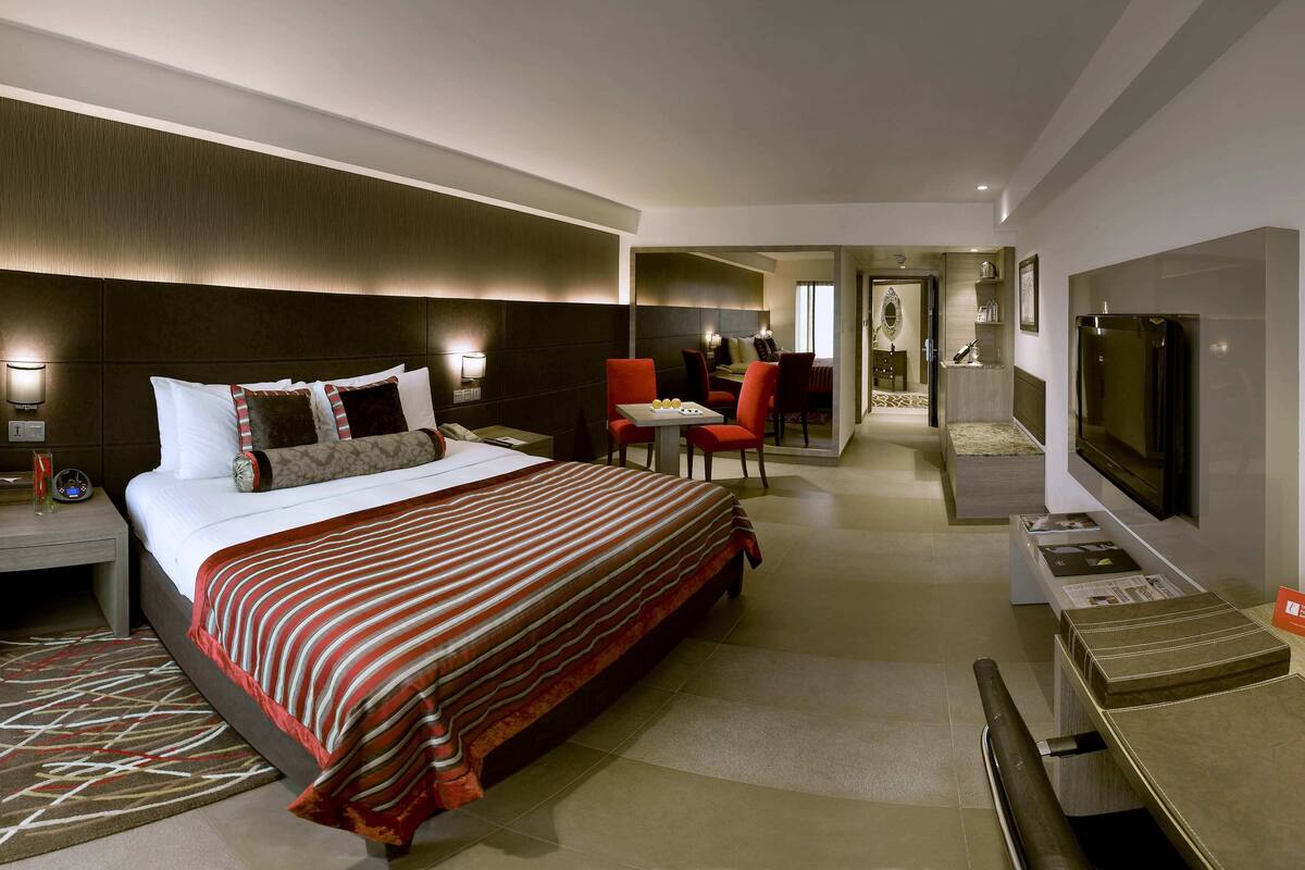 Ein Hotelzimmer mit einem großen Bett, einem Schreibtisch, einem Fernseher und einer Essecke.