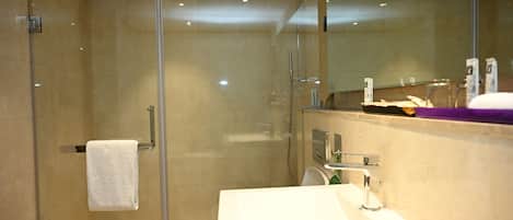 A modern bathroom with a glass-enclosed shower, a white sink, and a mirror above the sink.