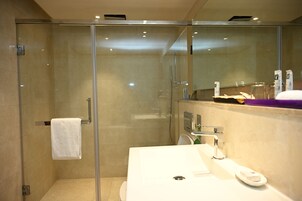 A modern bathroom with a glass-enclosed shower, a white sink, and a mirror above the sink.