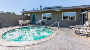 A swimming pool with lounge chairs, a small patio area, and a building with windows and a door. - Rodeway Inn Ontario Airport Mills (Ontario)