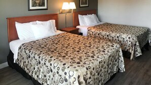 A hotel room with two beds, each with a patterned bedspread, a nightstand with a lamp, and framed artwork on the wall. - Rodeway Inn Ontario Airport Mills (Ontario)