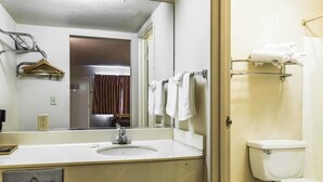 A bathroom with a sink, mirror, hanging towels, and a toilet. - Rodeway Inn Ontario Airport Mills (Ontario)