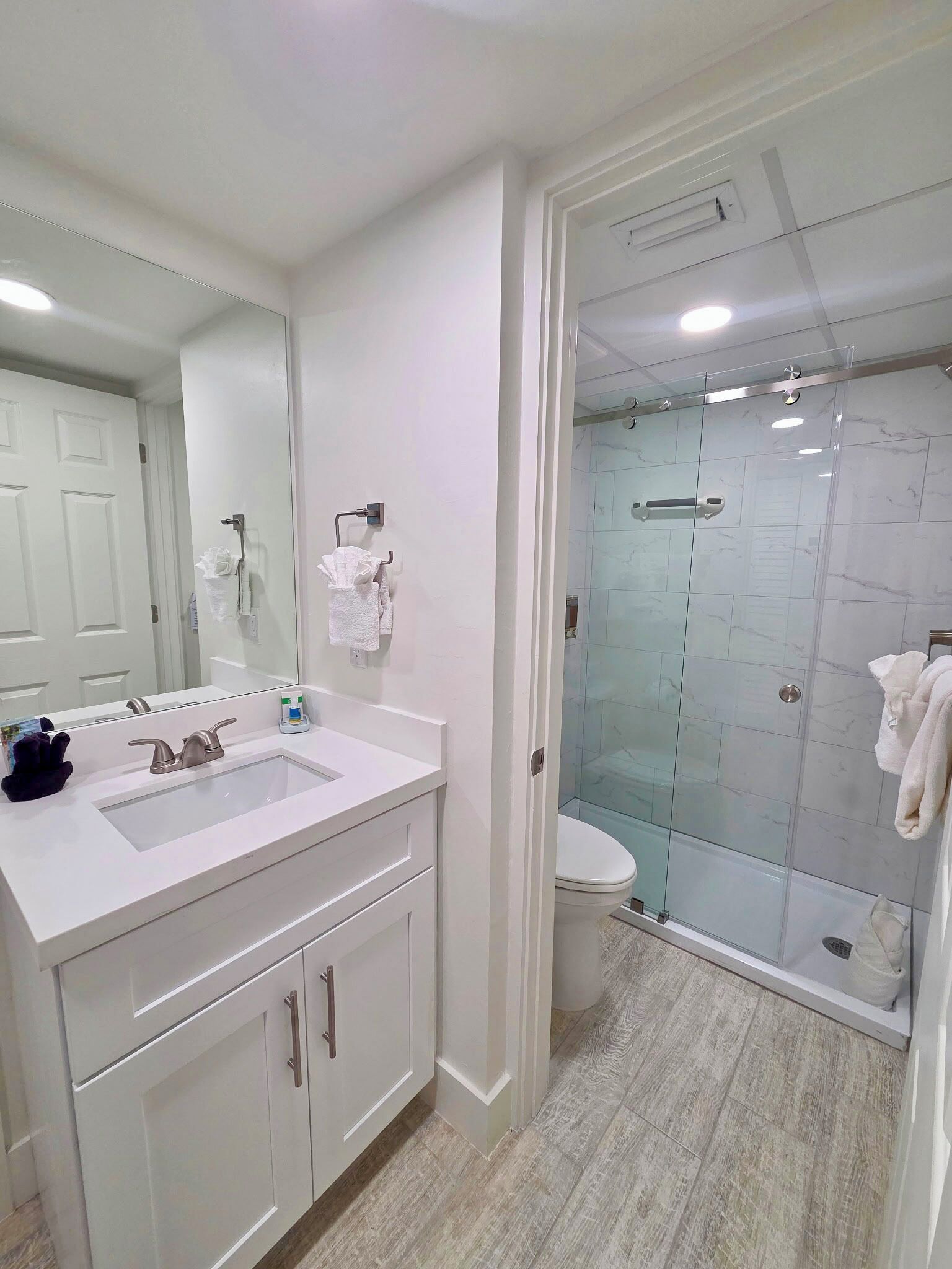 Une salle de bain moderne avec un grand miroir, un lavabo et une douche à parois de verre.
