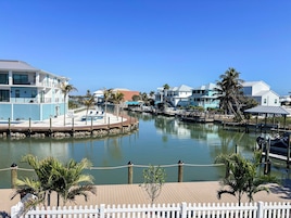 A waterfront property with a dock, a white picket fence, and a clear blue sky.