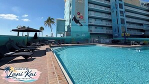 Un hôtel doté d’une piscine, de chaises longues et de palmiers.