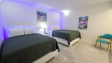 A hotel room with two beds, a chair, and artwork on the walls.