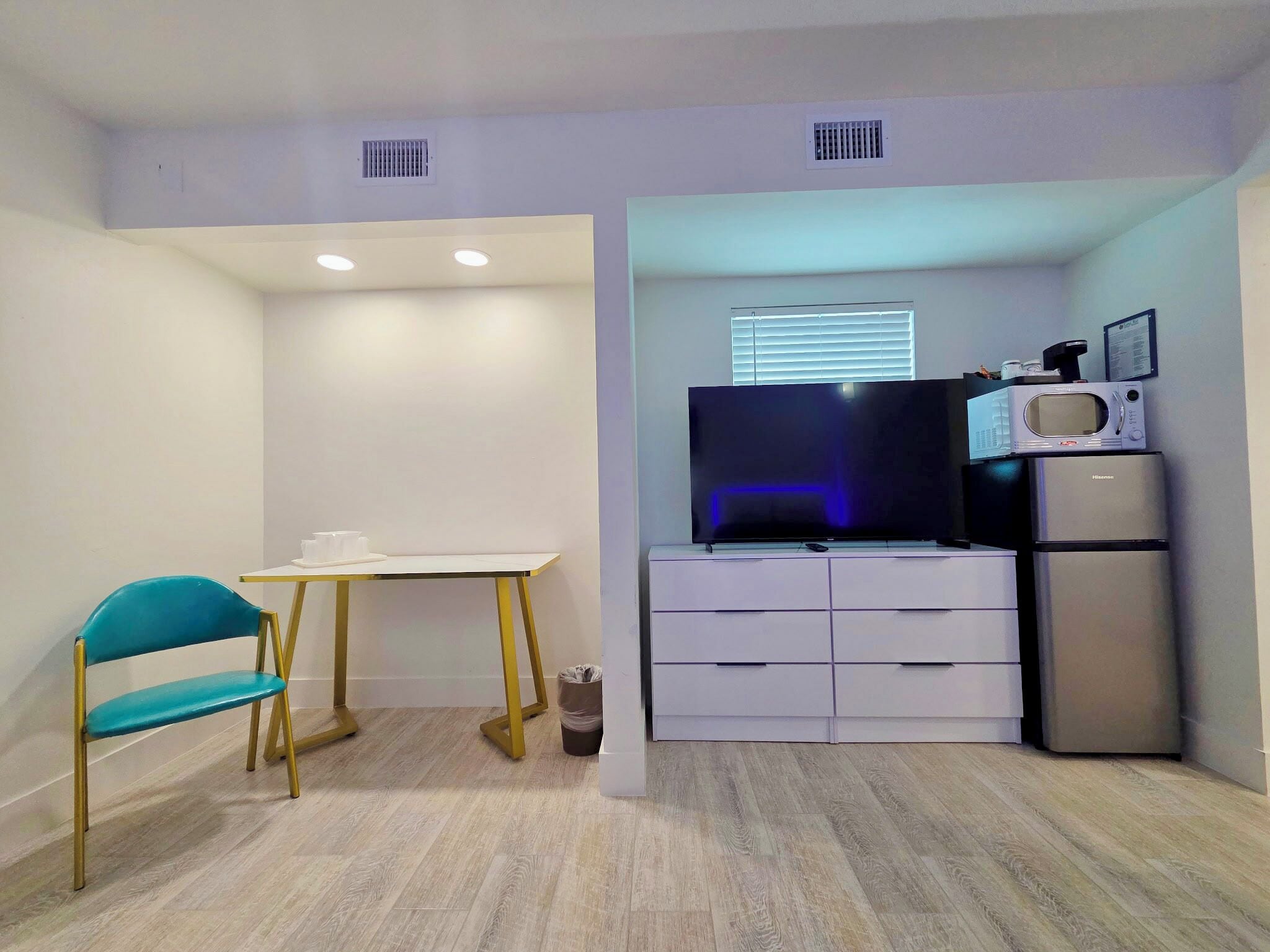 A compact kitchenette with a microwave, refrigerator, and a flat-screen TV.