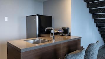 Una cocina moderna con refrigerador empotrado, un lavamanos y una cafetera.