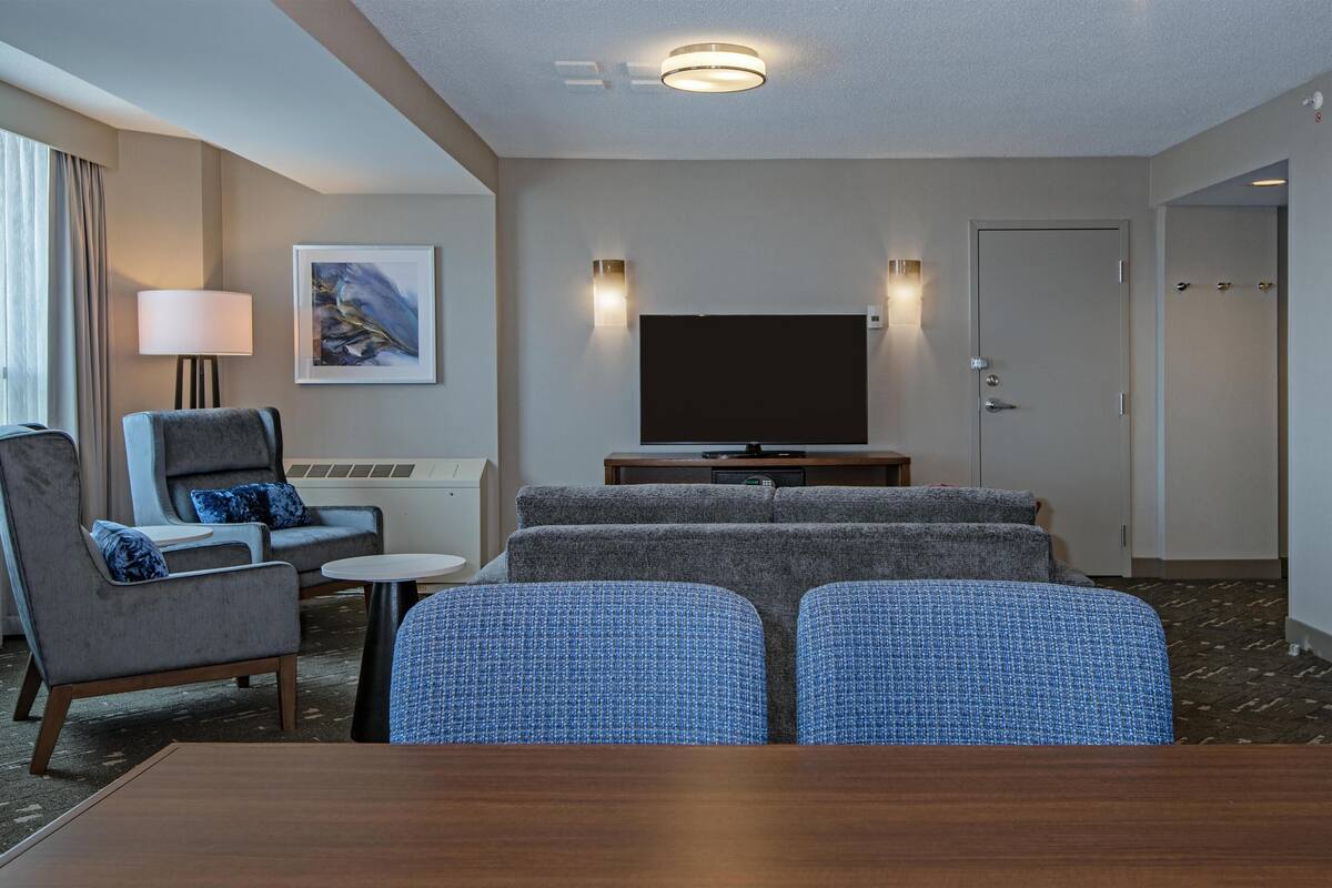 A hotel room with a sofa set, a TV, a lamp, and a framed picture on the wall.