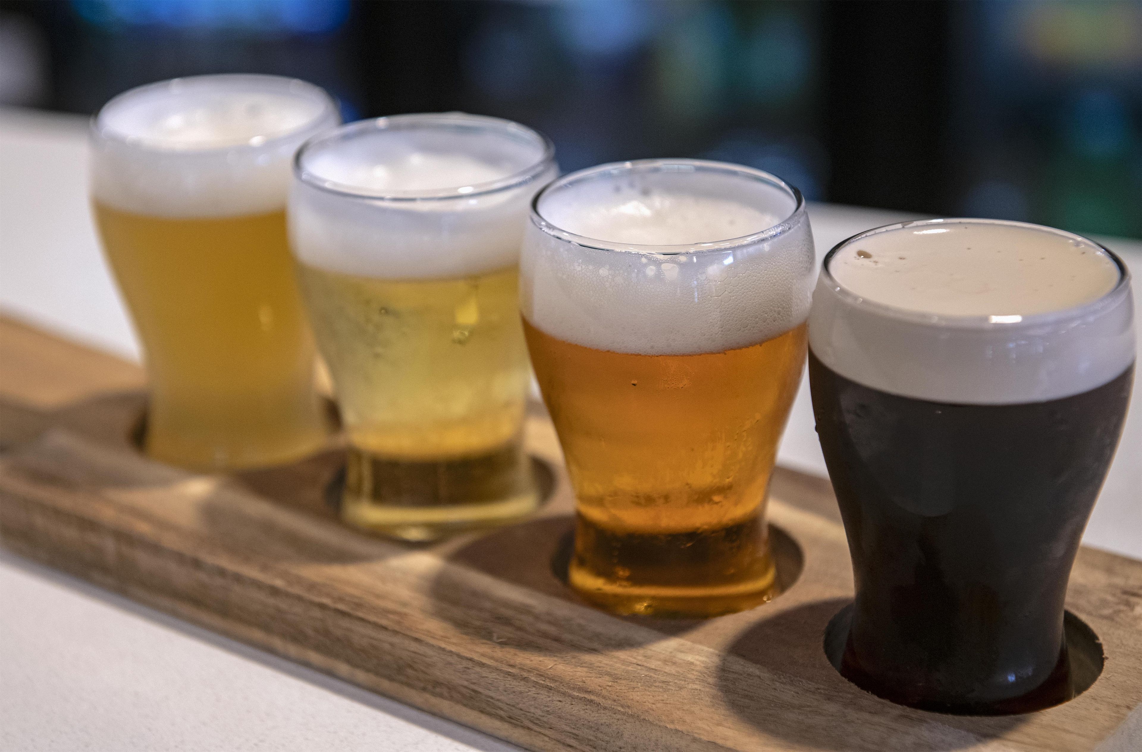 Quatre verres de bière sur un plateau en bois.