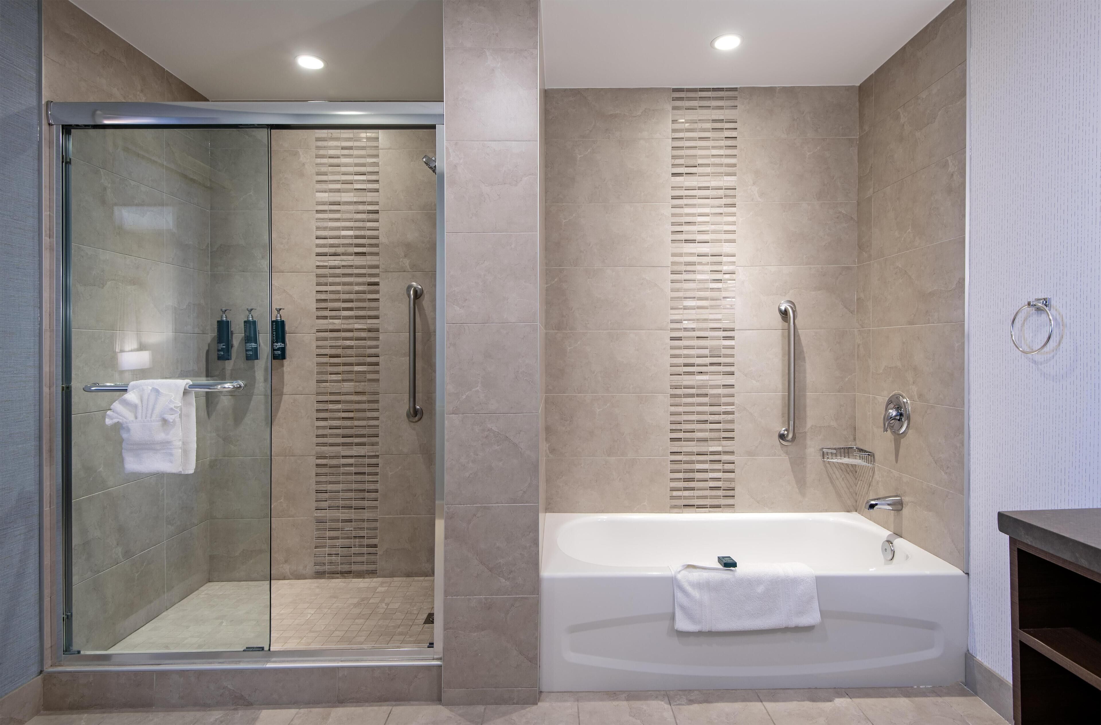 A modern bathroom with a glass-enclosed shower, a standalone bathtub, and a vanity with a towel ring.