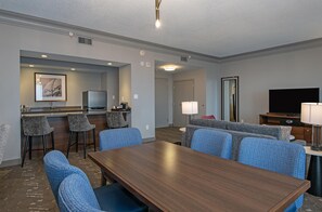 A hotel room with a dining table, bar stools, a sofa, a TV, and a lamp. - DoubleTree by Hilton Hotel West Edmonton (Edmonton)