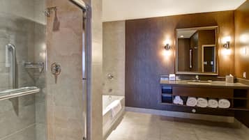 A modern bathroom with a glass-enclosed shower, a bathtub, and a vanity with a mirror and towel rack.