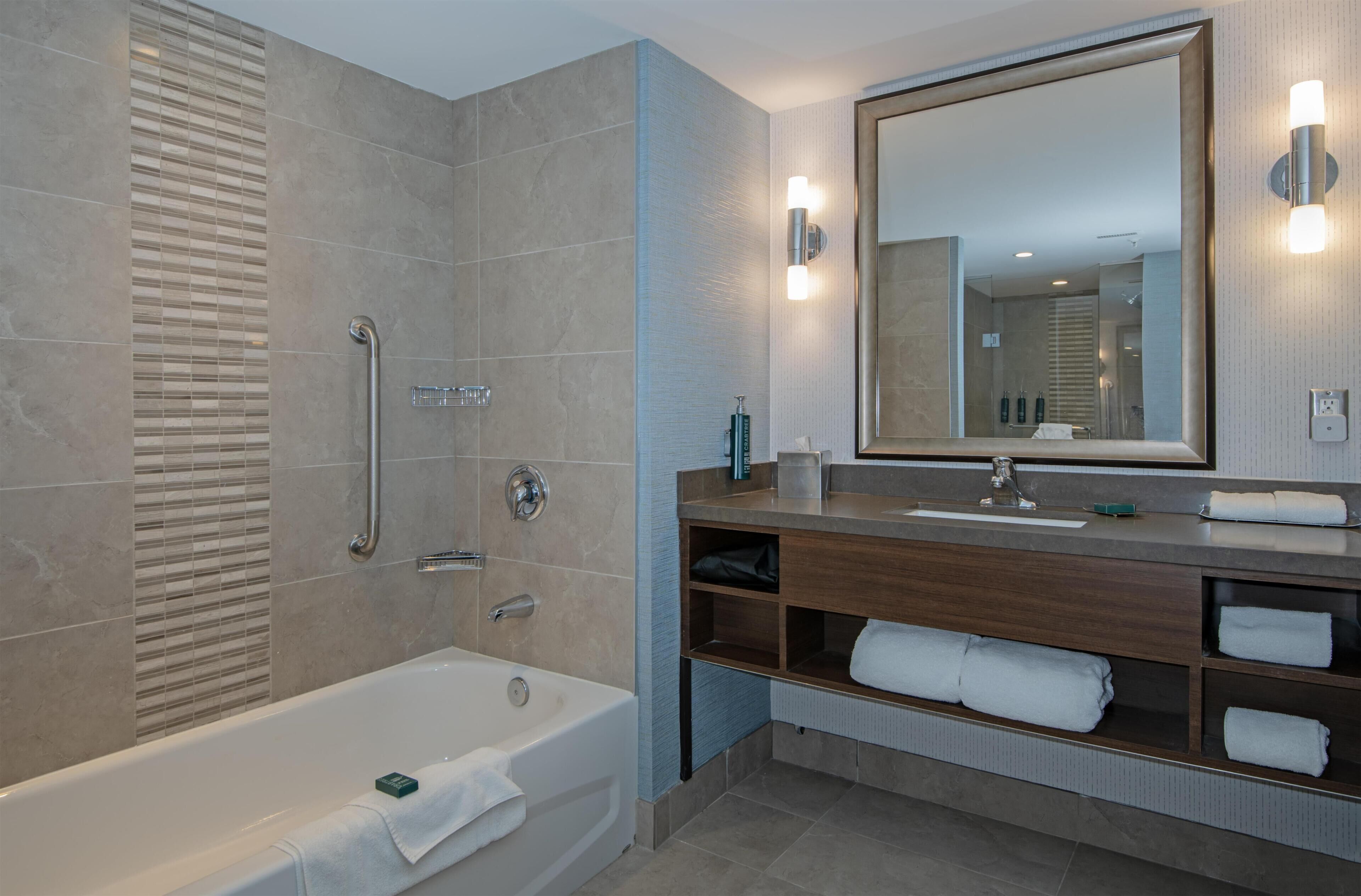 Une salle de bain moderne avec une baignoire, un meuble-lavabo avec un miroir et un espace douche.