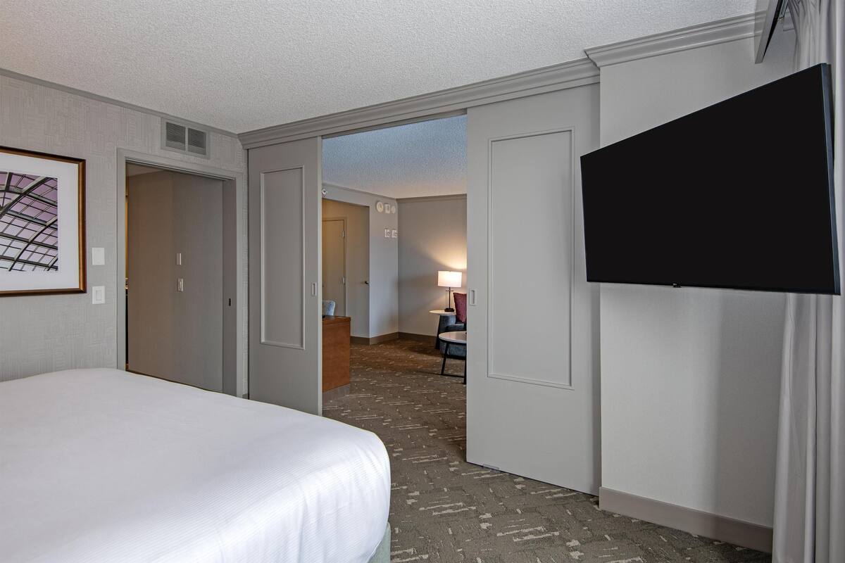 A hotel room with a bed, a TV, a desk, and a chair.