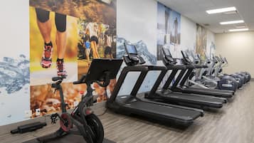 Een sportschool met meerdere loopbanden en een elliptische machine.