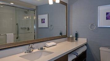 Un baño moderno con un espejo grande, lavamanos dobles, ducha y retrete.