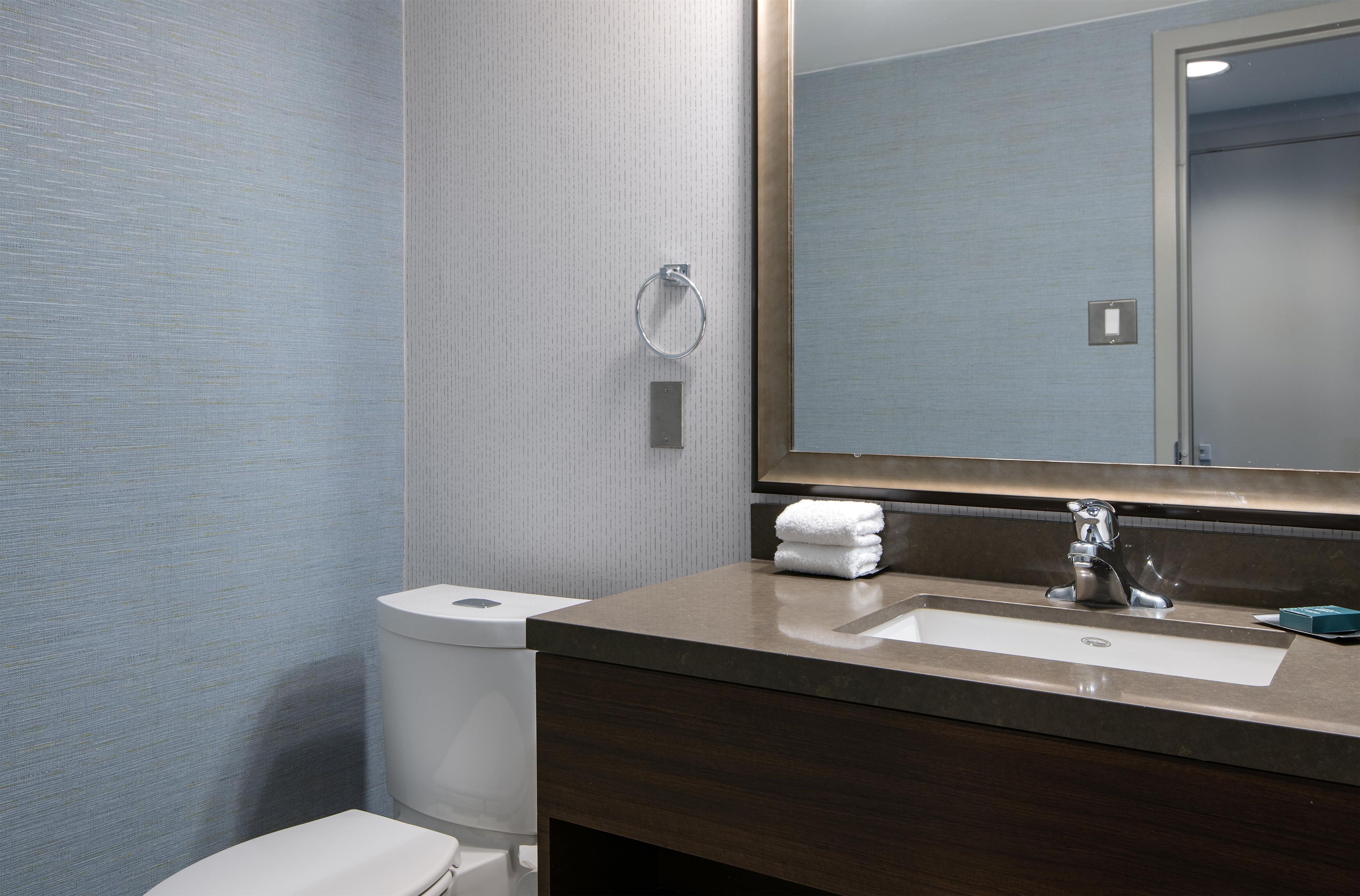 A bathroom with a toilet, sink, and mirror.