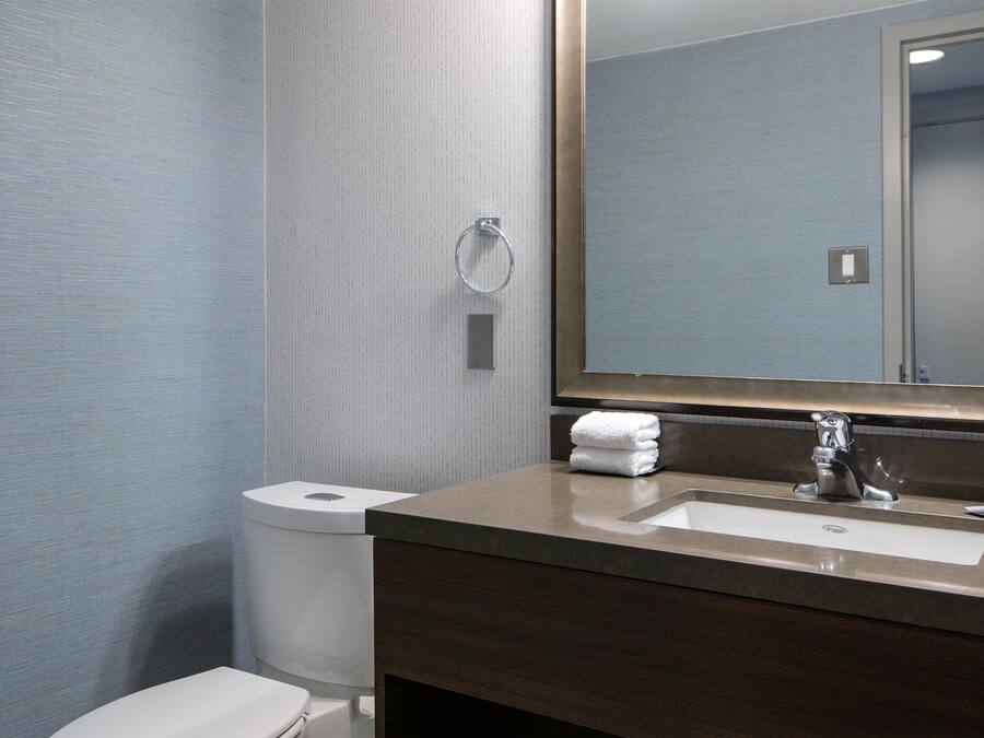 A bathroom with a toilet, sink, and mirror.