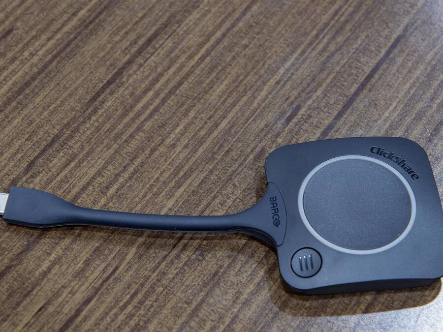 Un câble USB noir avec une molette de défilement sur une surface en bois.