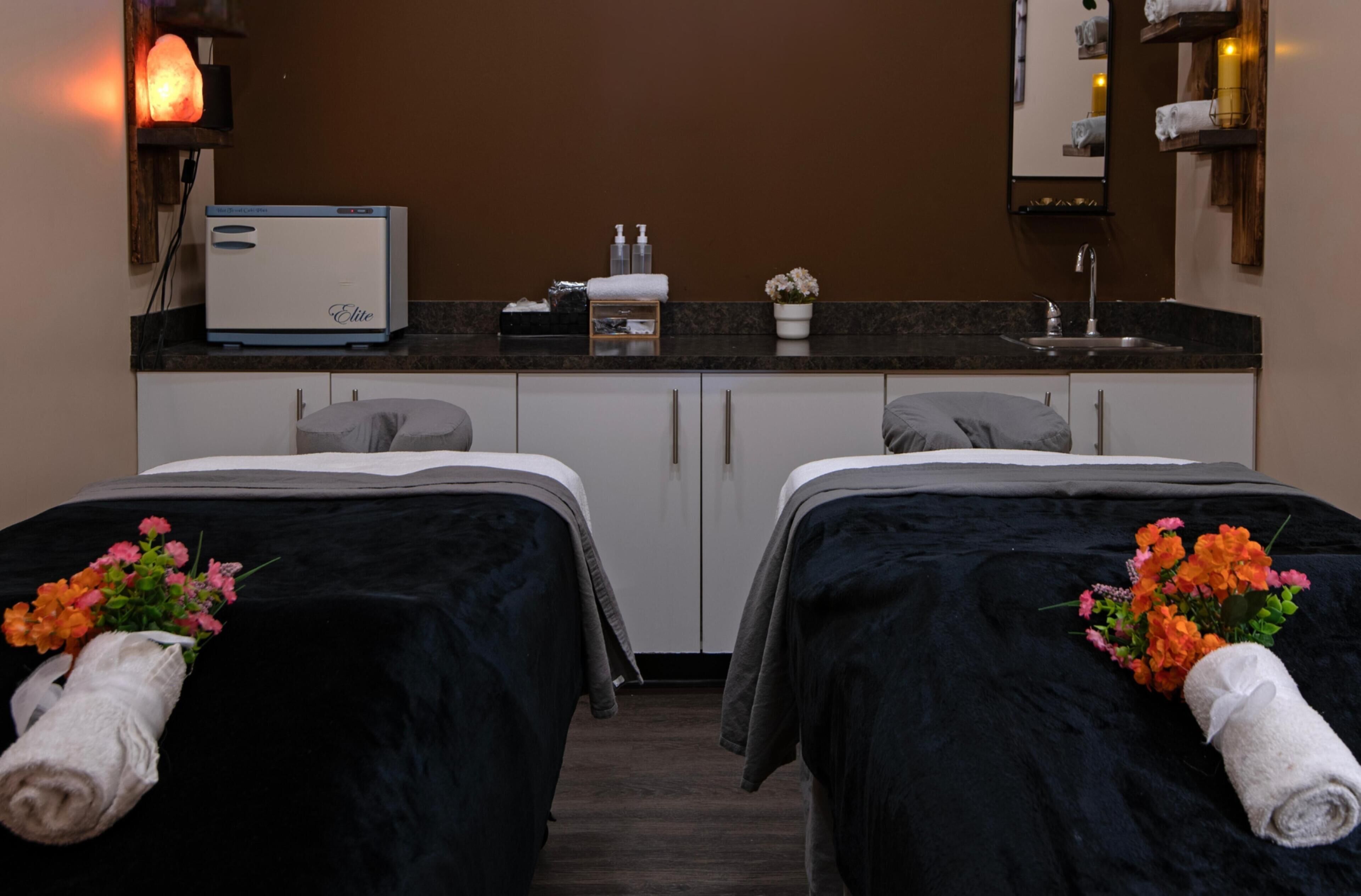 A hotel room with two beds, a small kitchenette, a mirror, and a heater.