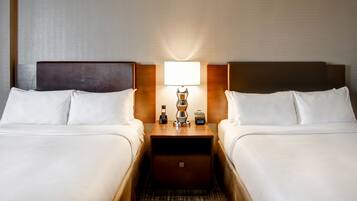 A hotel room with two beds, a nightstand with a lamp, a radio, and a phone.