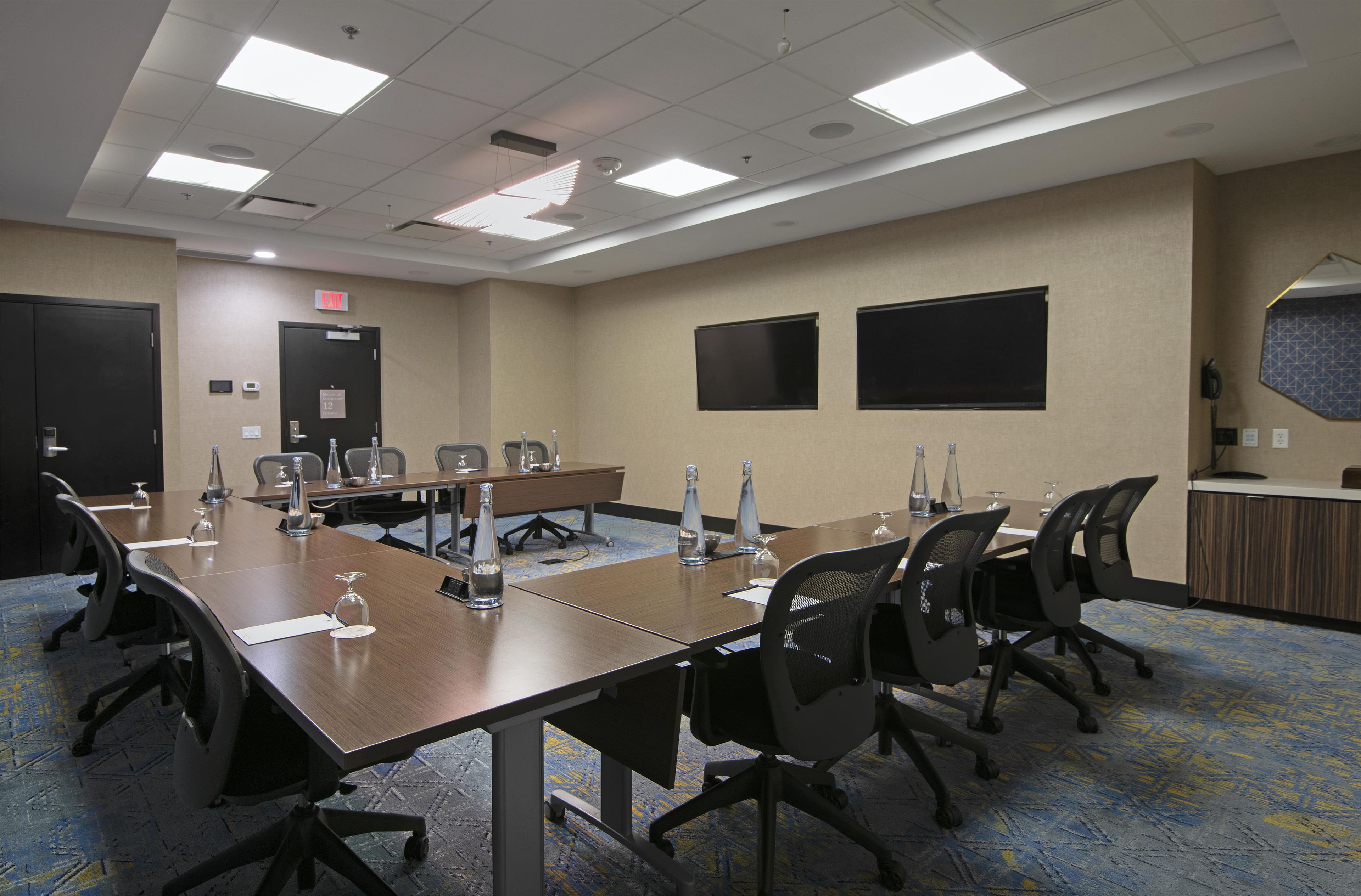A conference room with a long table, chairs, and a carpeted floor.