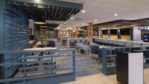 Un lobby moderno de hotel con áreas de descanso, un bar y una recepción.