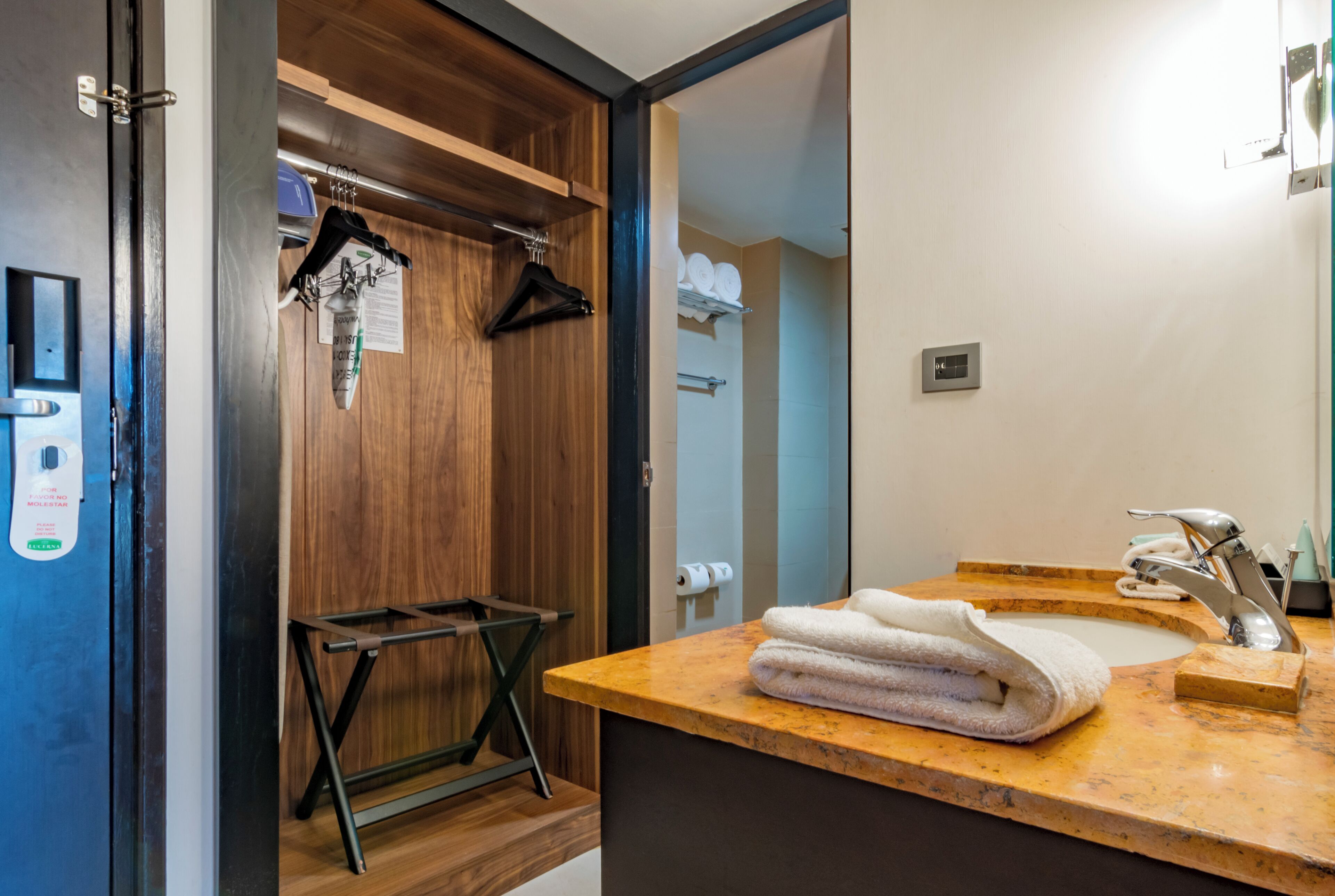 A bathroom with a wooden door, a sink with a marble countertop, and a towel rack.