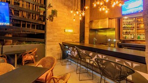 A bar area with wicker chairs, a counter, and a TV screen. - Hotel Lucerna Mexicali (Mexicali)