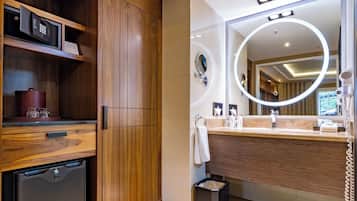 Un baño moderno con tocador de madera, secador de pelo incorporado y espejo con luz circular.