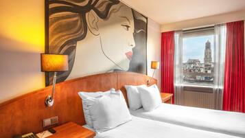 A hotel room with a large bed, two bedside tables, a telephone, and a painting on the wall.