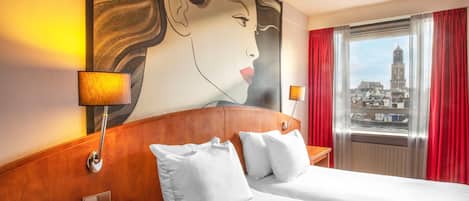 A hotel room with a large bed, two bedside tables, a telephone, and a painting on the wall.