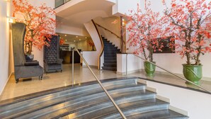 A modern hotel lobby with a curved staircase, plush seating, and decorative plants. - Leonardo Hotel Utrecht City Center (Utrecht)