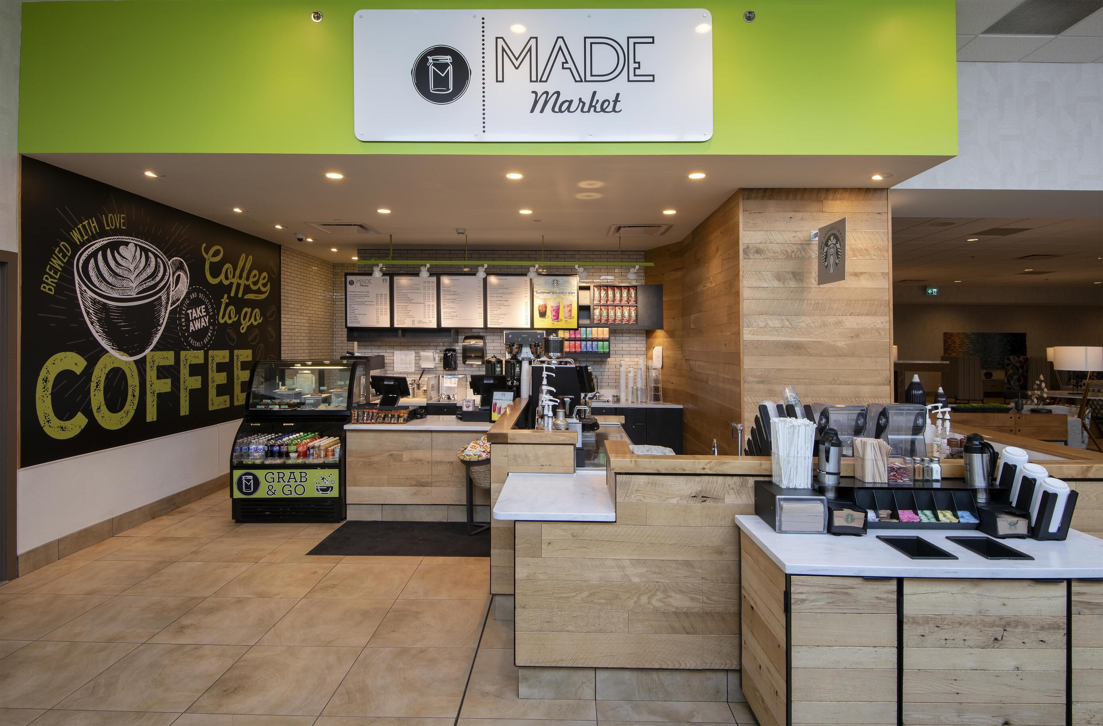 A coffee shop interior with a 'Grab & Go' station, a menu board, and a Starbucks logo on the wall.