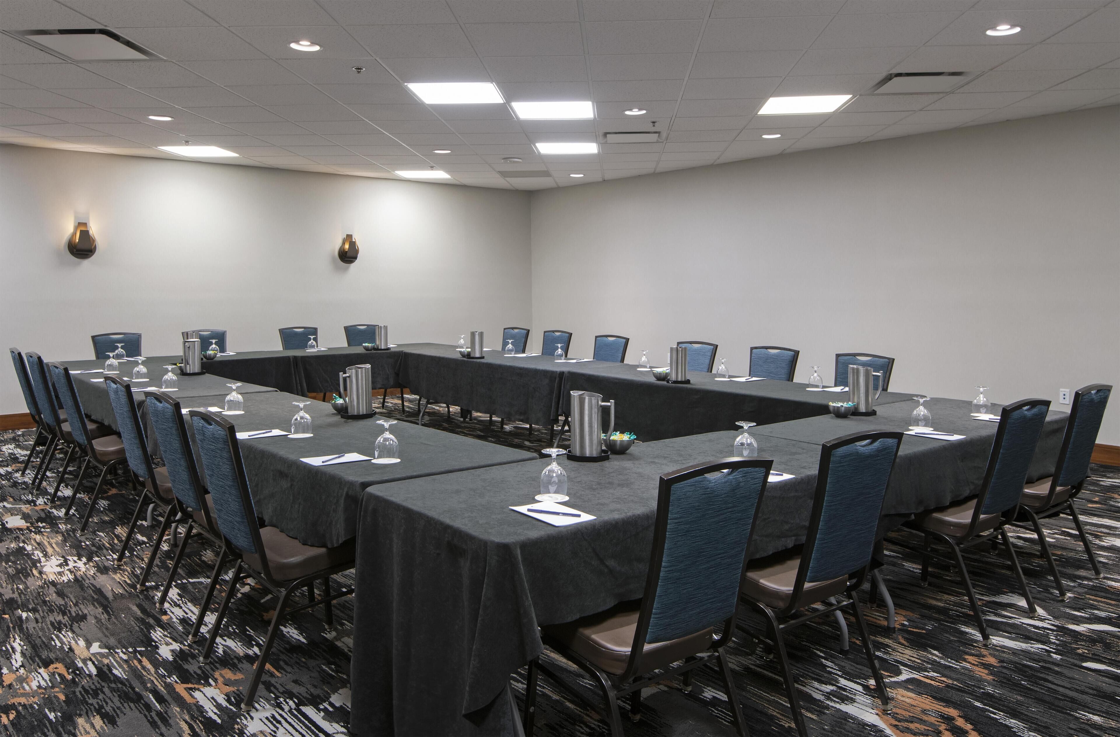 A conference room with a long table, chairs, and water glasses.