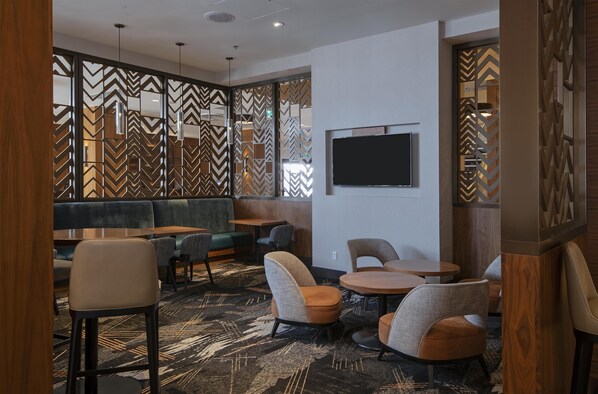 A modern lounge area with seating arrangements, a flat-screen TV, and decorative wall panels.