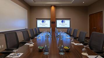 A conference room with a long table, chairs, and a projector screen displaying the DoubleTree logo.