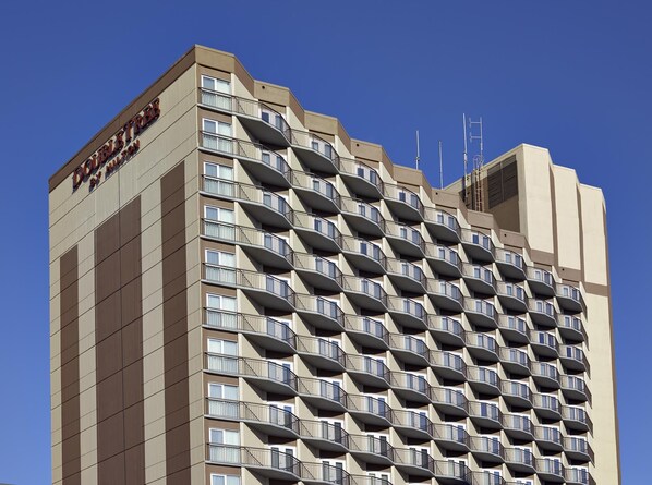 A high-rise hotel with a repeating balcony pattern, multiple antennas, and a clear sky.