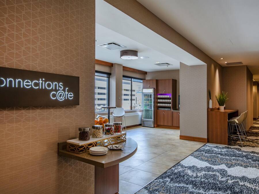 Un moderno vestíbulo de hotel con mostrador de recepción, zona de bufé y área de descanso.